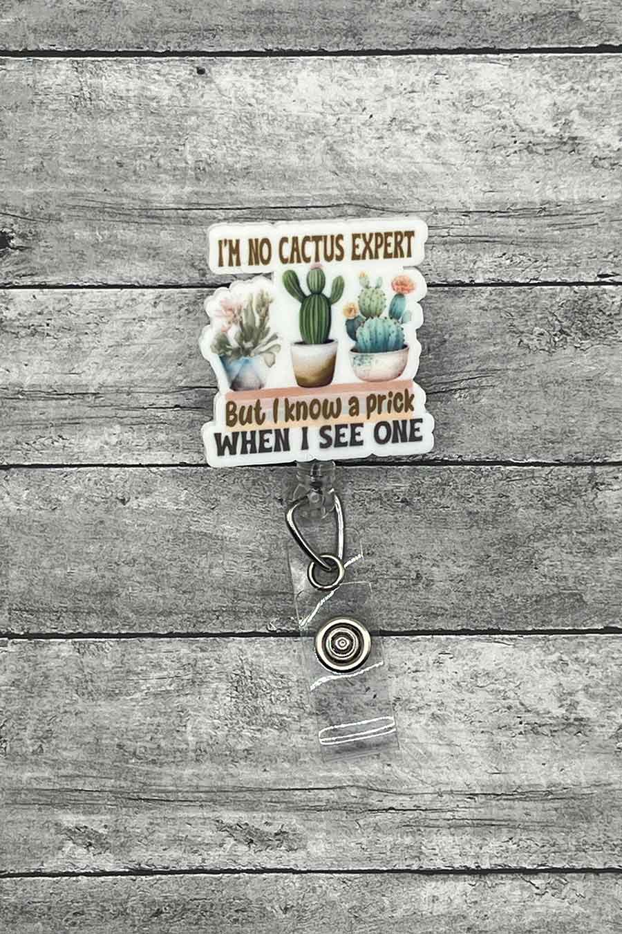 "Cactus Humor Badge Reel featuring the phrase 'I'm No Cactus Expert But I Know a Prick When I See One' with a charming illustration of various cacti.
