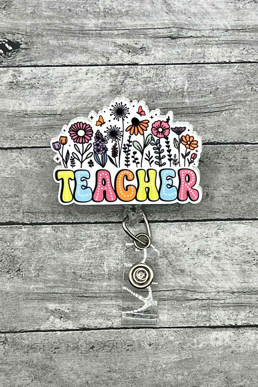 Wildflower Whimsy Teacher Badge Reel featuring a colorful design with various flowers and the word 'TEACHER' in playful, multi-colored letters.